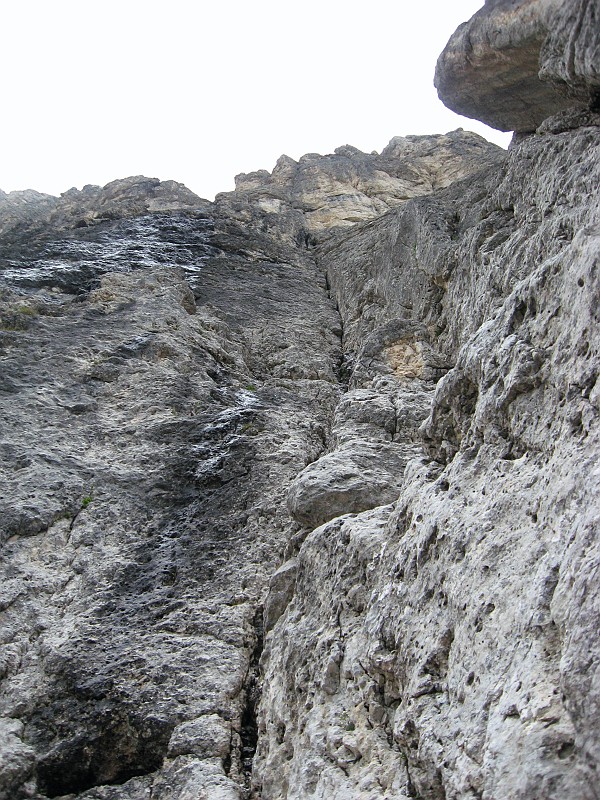IMG_0004.JPG - L'attacco della via. Il percorso è molto logico e segue l'evidente fessura che in prossimità della cima diventa uno stretto canale. Salgo sul primo tiro con qualche perplessità non trovando chiodi. Un solo chiodo alla sosta.