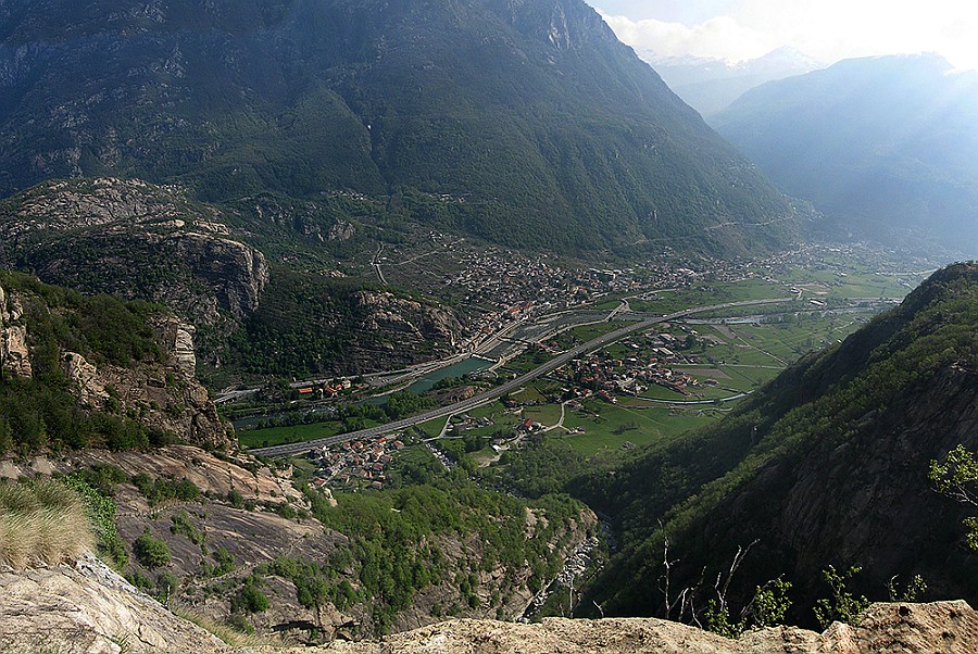 PanoramaDalTraliccio.jpg - Via recente sulla parete del Fer.  Accesso: Da Donnas seguire le indicazioni per  Outrefer e parcheggiare appena prima del paese. Seguire poi la mulattiera a gradini n° 5 per Pian Bosonin per circa tre quarti d'ora fino all'evidente indicazione per il Pilastro Neri Camilla. Scavalcare qui la staccionata , e seguire i bolli gialli nel bosco di castagni incontrando poco dopo una corda fissa.  Arrivare ad un traliccio ( da cui è stata scattata questa foto ). Dal traliccio seguire ancora per poche decine di metri i bolli gialli e rossi poi abbandonare i bolli che portano a una lunga cengia a destra,  costeggiando invece  la parete verso sinistra ( niente bolli ma un paio d'ometti e tracce ). L'attacco della via Dolce Fer  è il primo che si incontra. Scritta alla base. Calcolare un'ora e mezza dal parcheggio.